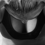 Black and white photo of a woman in sports attire reflecting in thought.
